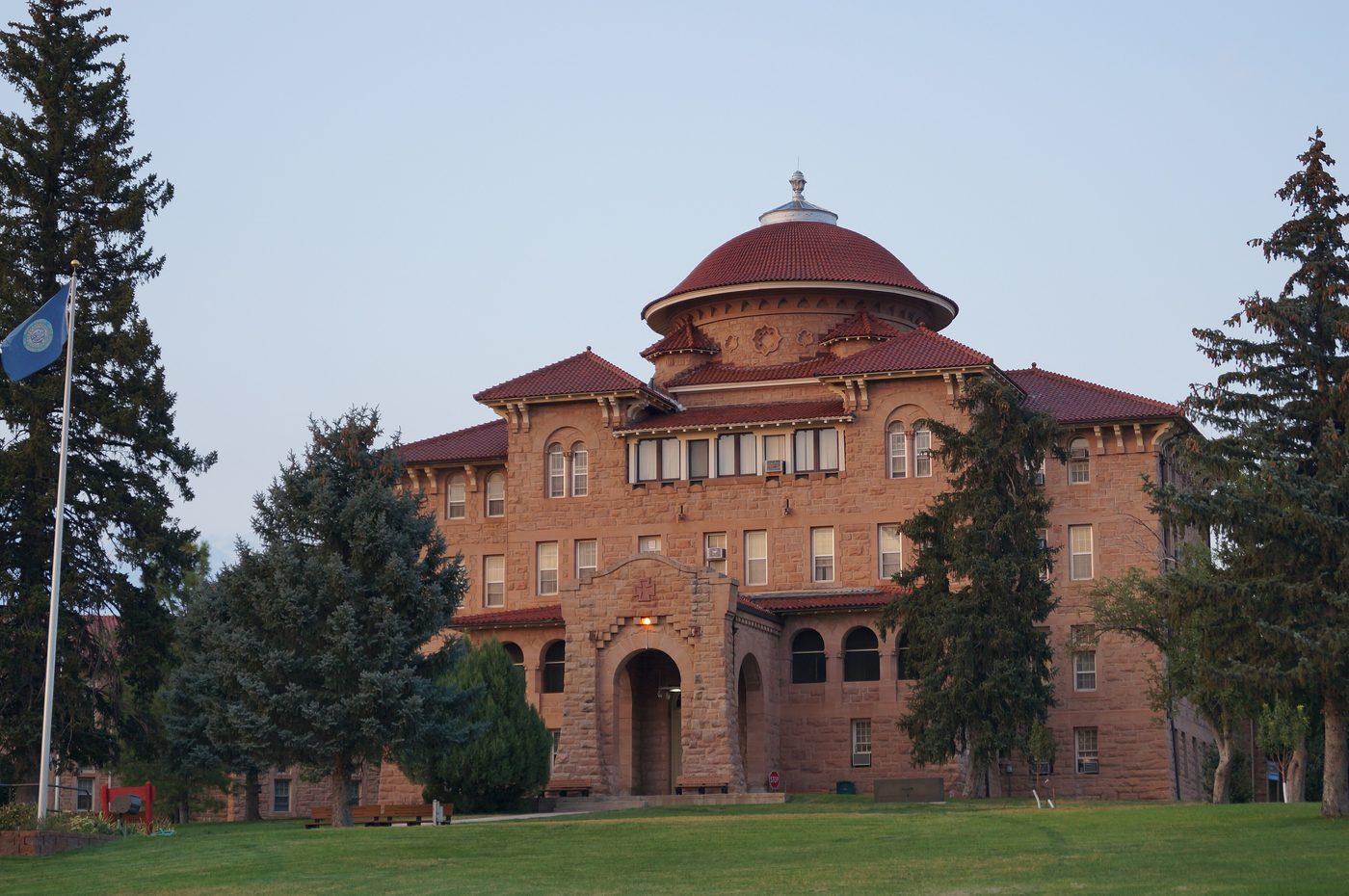 Historic Battle Mountain Sanitarium, a red-roofed sandstone building among pine trees in Hot Springs, SD